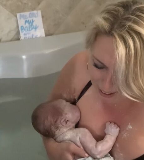 Mom holds newborn in birth tub
