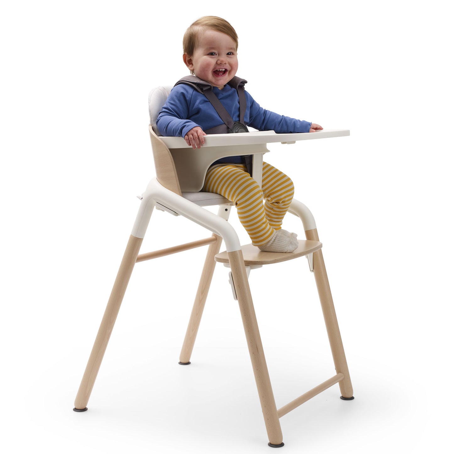 Baby sits in Bugaboo Giraffe High Chair Complete - Natural Wood/White