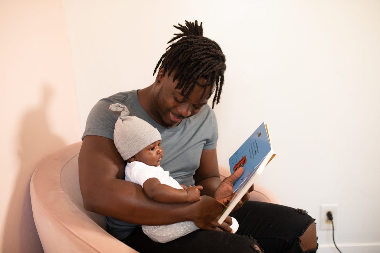 A loving father reads a book to his baby, fostering an affectionate bond.