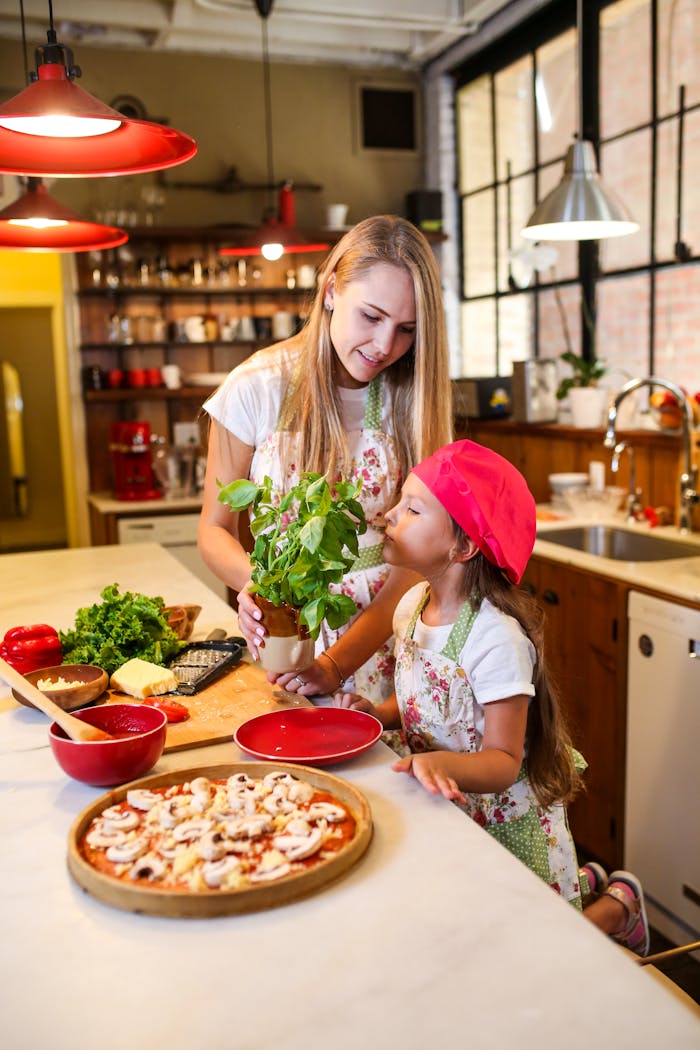 A joyful mother and daughter duo cooking pizza together in their cozy kitchen.